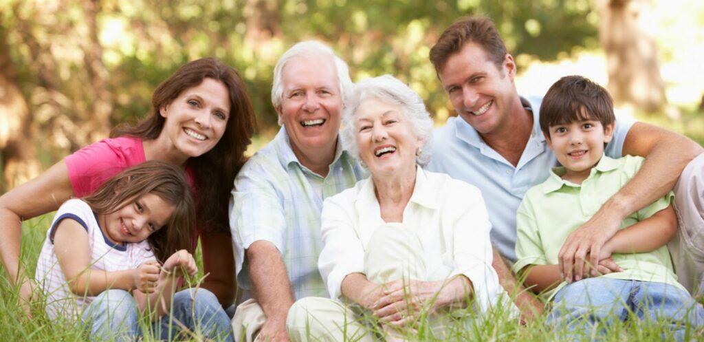 family of 6 sitting on grass smiling